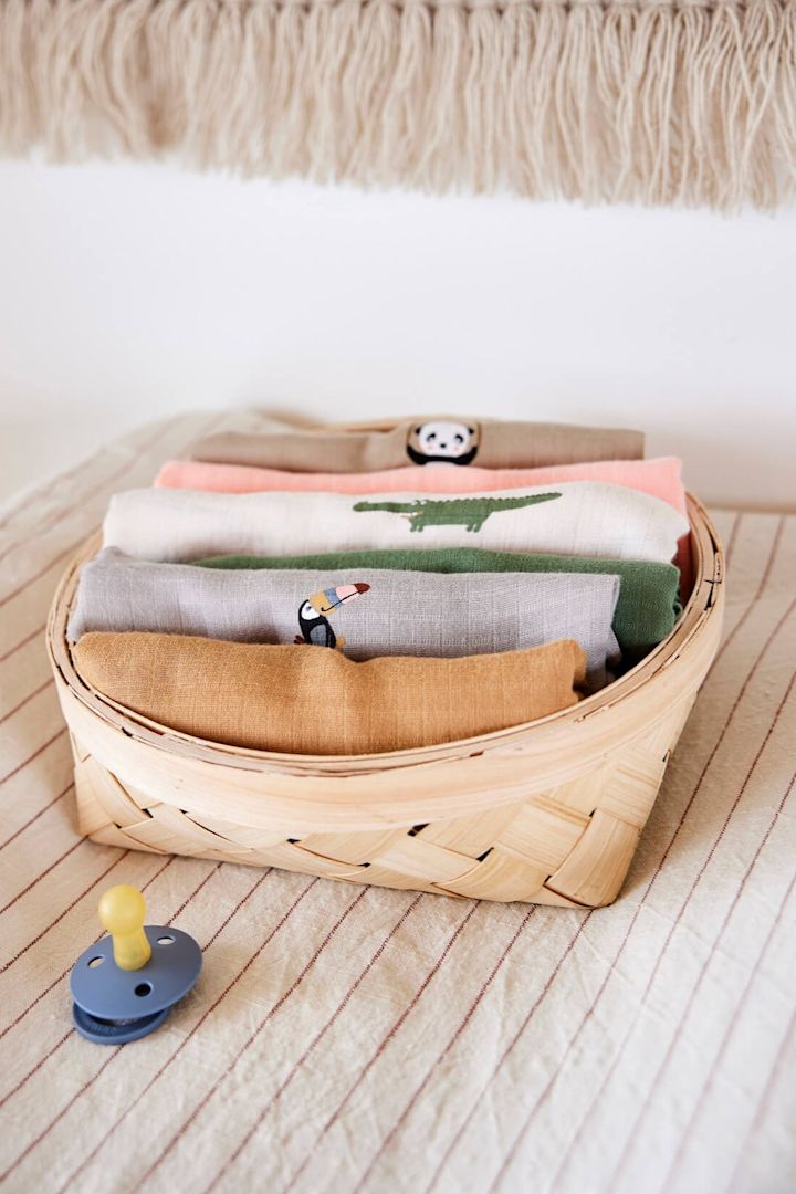 Las mantas de muselina son una apuesta segura cuando se trata de ideas de regalos para baby shower. Aquí tienes mantas de OYOY en diferentes colores en una cesta.