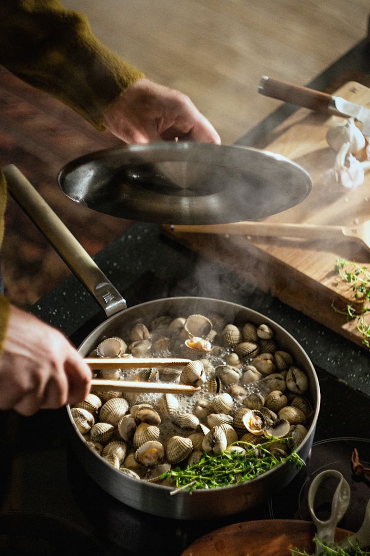 Una persona prepara mejillones en la sartén de acero inoxidable Norden Steel de Fiskars.