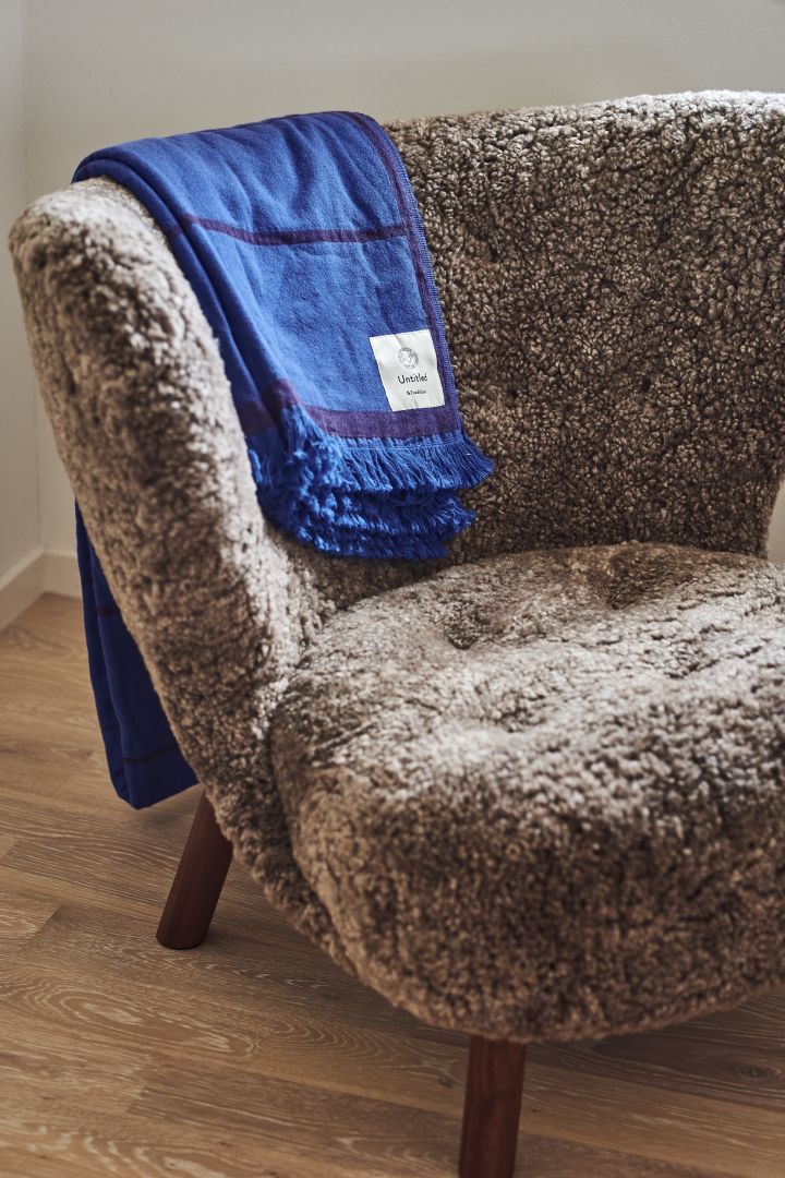 Aquí puedes ver el sillón Little Petra en una variante de piel de oveja esponjosa con la manta azul Untitled encima, ambas de &tradition. 