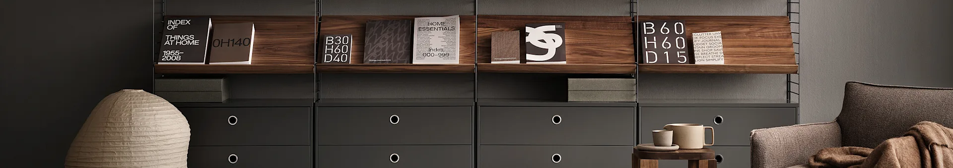 Estantería moderna con estantes de madera oscura, cajones grises, libros, un jarrón claro, un sillón marrón y accesorios de cerámica.