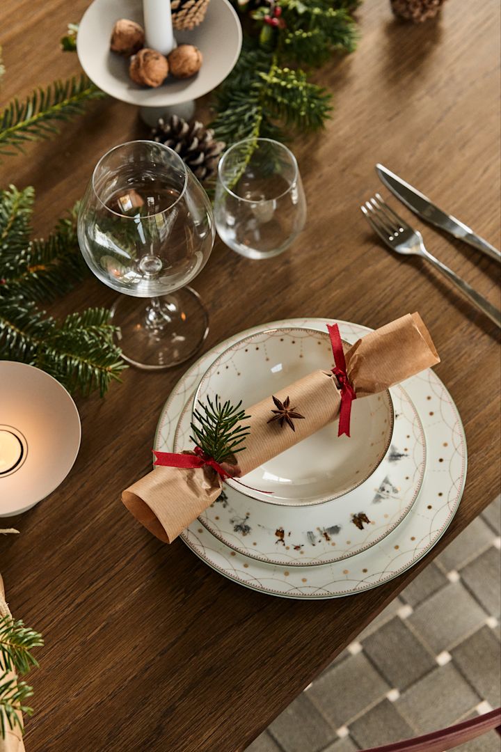 Decora con ramas de abeto en la mesa puesta junto con la vajilla Julemorgen de Wik & Walsøe para crear un ambiente navideño durante la cena.