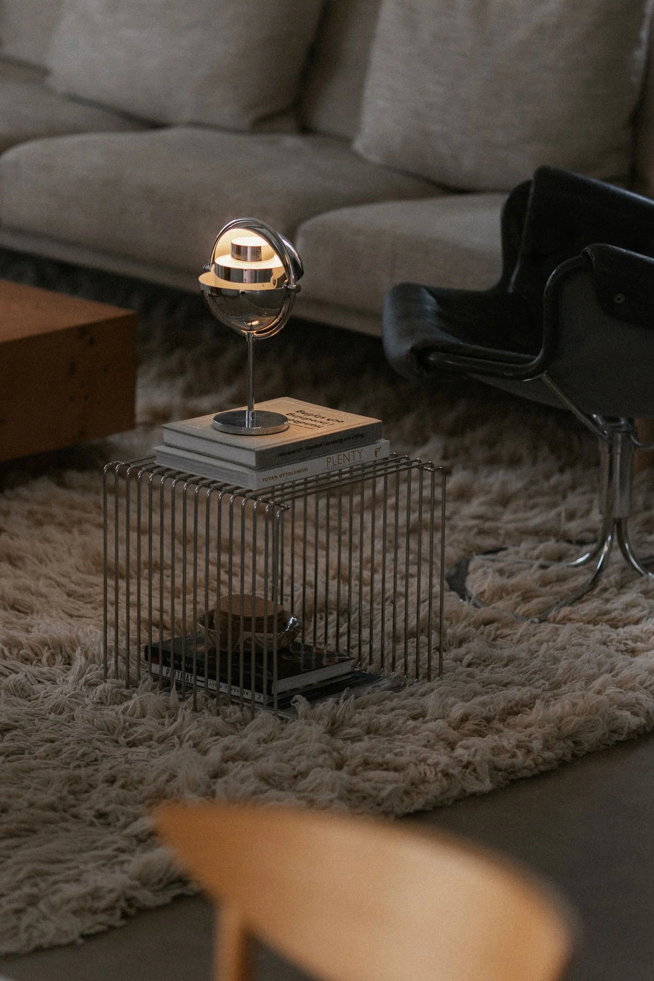 Lámparas escandinavas: la lámpara de mesa Multi-Lite de Gubi en acabado cromado está en un salón, sobre una estantería Panton Wire.