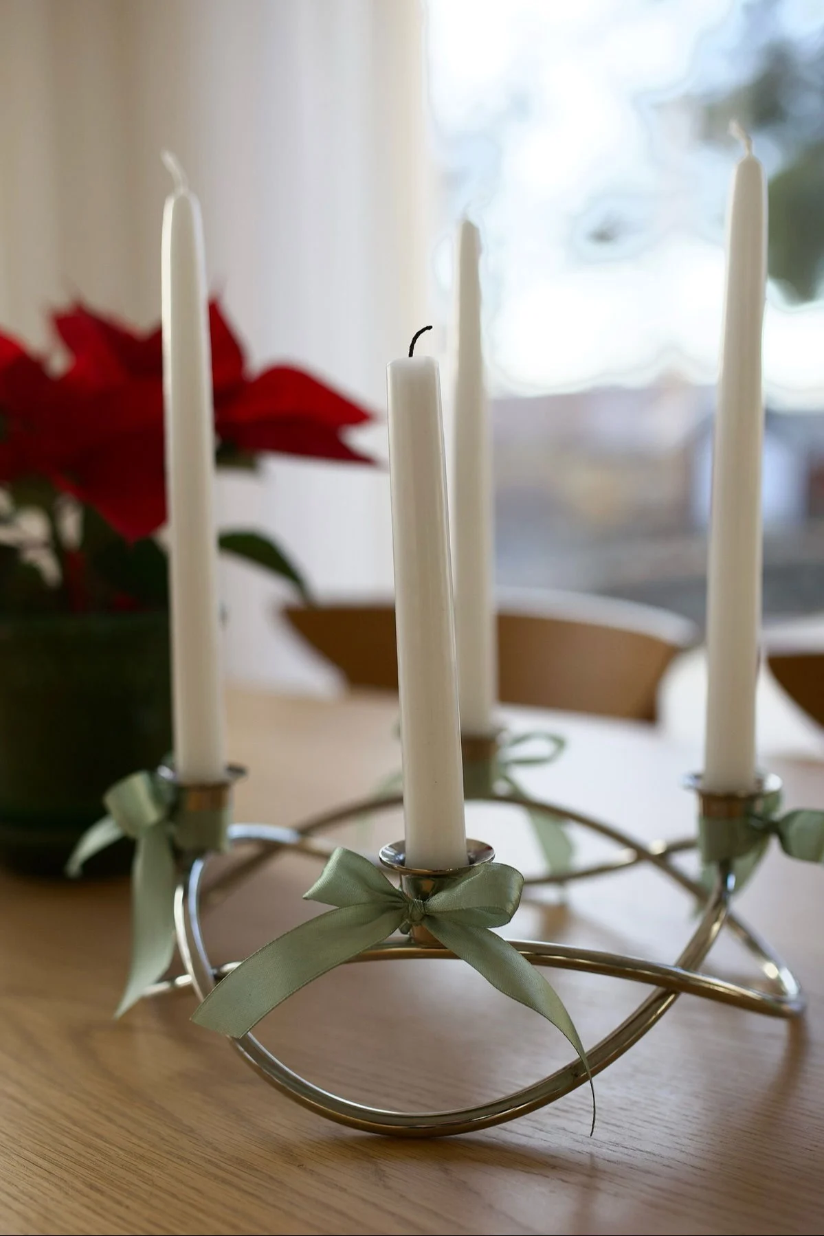 El portavelas Season de Georg Jensen, plateado y decorado con lazos, está sobre una mesa.