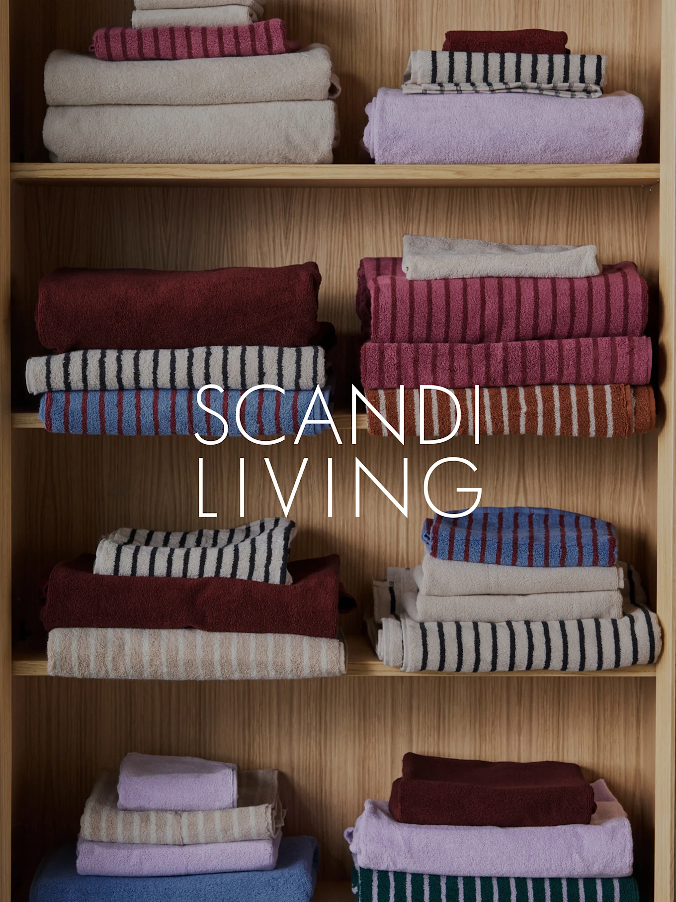 Texto SCANDI LIVING sobre toallas apiladas y dobladas en varios colores y patrones en estantes de madera.