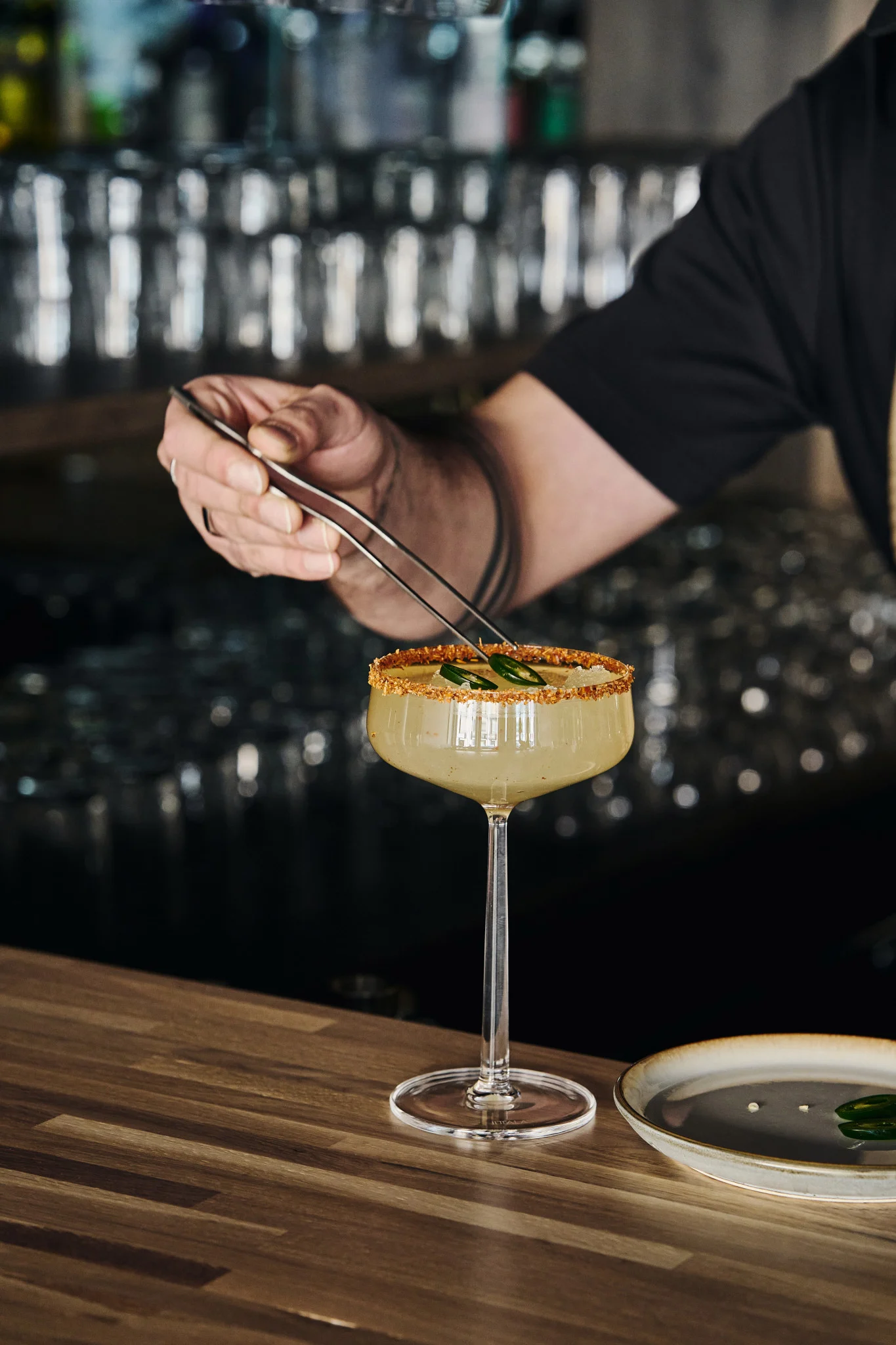 Perfectas para cócteles sin alcohol: las copas de cóctel Essence de Iittala con bebida, borde decorado y adornadas con rodajas de jalapeño con pinzas.