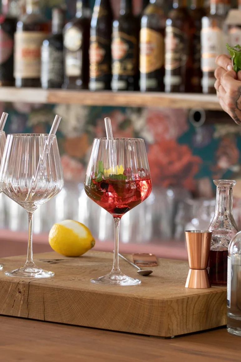 Un cóctel sin alcohol en un vaso Feel Good G&T de Nachtmann sobre una tabla de madera frente a una barra.