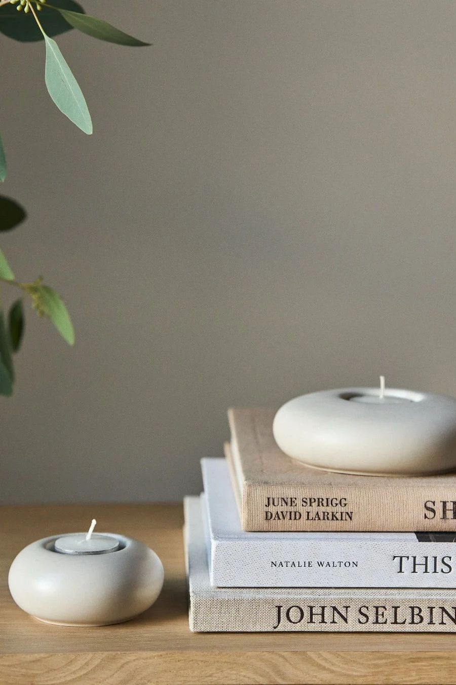 Lagom: Una pila de libros con un portavelas Stone de Scandi Living.