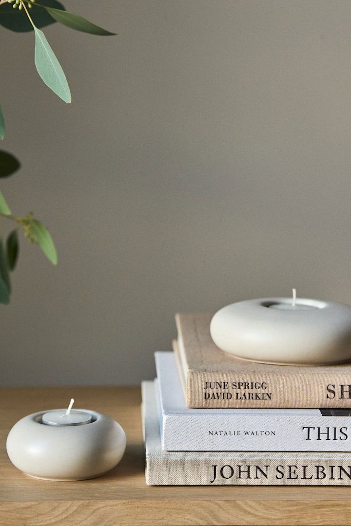Lagom: Una pila de libros con un portavelas Stone de Scandi Living.